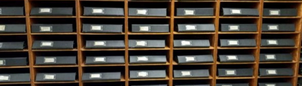 Wall of labeled mail slots in a wooden sorting cabinet.