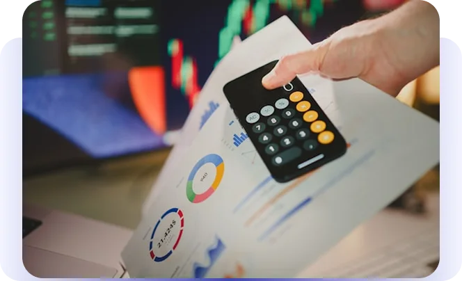 Hand using a calculator over printed financial charts and market data.