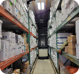 Warehouse aisle with stocked shelves and a pallet jack.