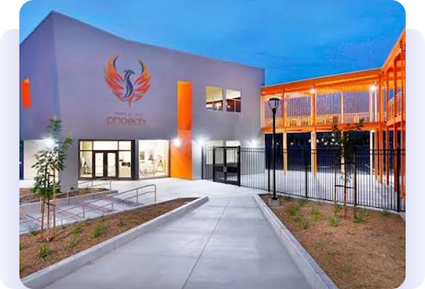 Phoenix-branded modern building entrance illuminated at dusk.